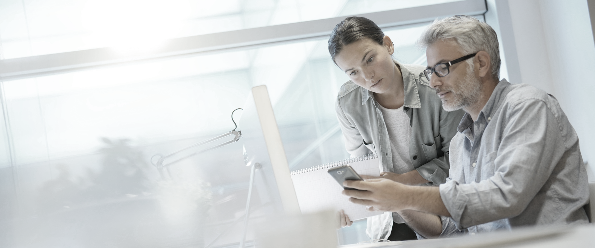 Banner Mann und Frau schauen au ein Smartphone von SYNAXUS auch für BI und CPM Consulting